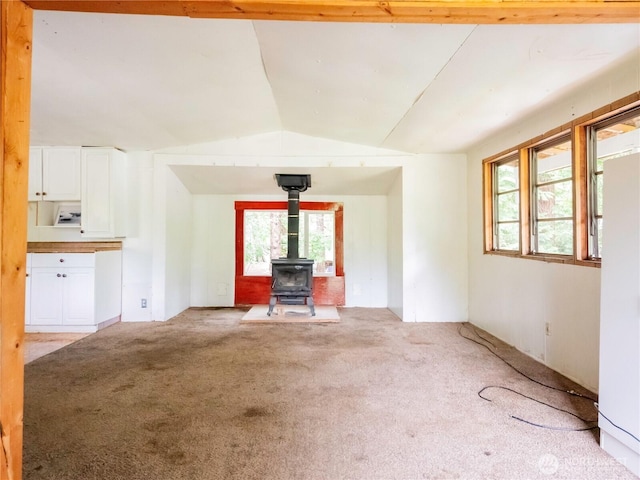 9712 Channel Dr NW, Olympia, WA 98502 - unfurnished living room with vaulted ceiling, light colored carpet, and a wood stove