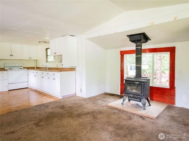 9712 Channel Dr NW, Olympia, WA 98502 - unfurnished living room featuring light colored carpet, vaulted ceiling, a wood stove, and a sink