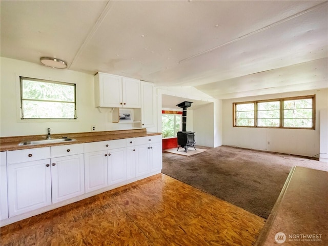 9712 Channel Dr NW, Olympia, WA 98502 - kitchen with a sink, a wood stove, white cabinets, and open floor plan