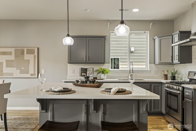 26216 SE 228th Ave SE Unit 26216, Maple Valley, WA 98038 - kitchen with stainless steel range with gas stovetop, gray cabinetry, wall chimney range hood, a kitchen bar, and light countertops