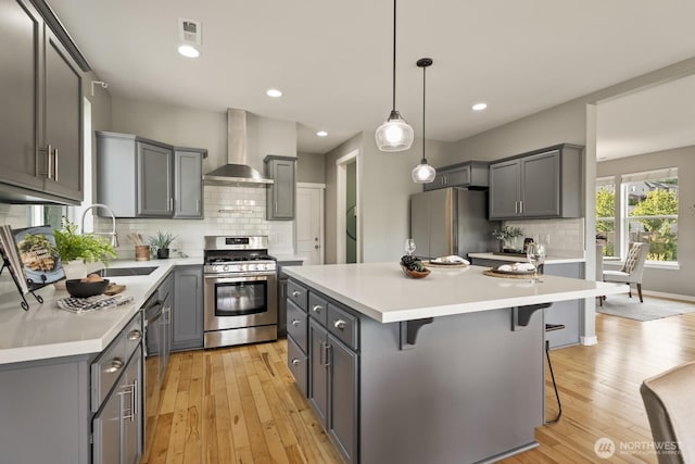 26216 SE 228th Ave SE Unit 26216, Maple Valley, WA 98038 - kitchen featuring stainless steel appliances, wall chimney exhaust hood, gray cabinets, a breakfast bar, and a kitchen island