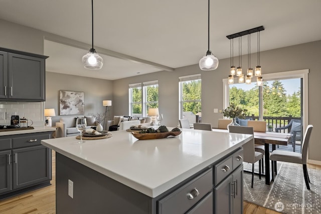 26216 SE 228th Ave SE Unit 26216, Maple Valley, WA 98038 - kitchen with gray cabinetry, light wood-style flooring, light countertops, a center island, and decorative backsplash