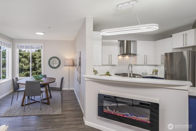 124 Bellevue Ave E Unit 305, Seattle, WA 98102 - kitchen featuring wall chimney range hood, freestanding refrigerator, baseboards, light countertops, and decorative backsplash