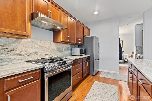8521 15th Ave SE, Olympia, WA 98513 - kitchen featuring stainless steel appliances, under cabinet range hood, light wood-type flooring, tasteful backsplash, and brown cabinetry
