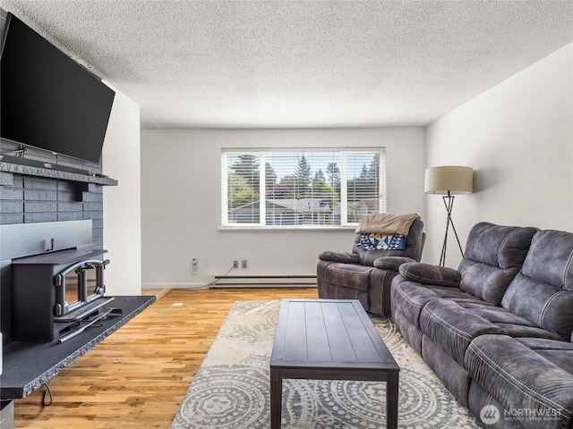 8828 S K St, Tacoma, WA 98444 - living area with a wood stove, baseboard heating, wood finished floors, a textured ceiling, and baseboards
