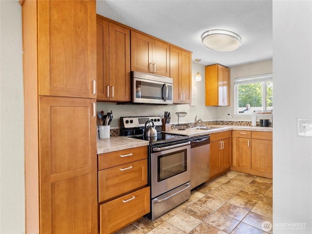 8828 S K St, Tacoma, WA 98444 - kitchen featuring appliances with stainless steel finishes, light countertops, a sink, and brown cabinets