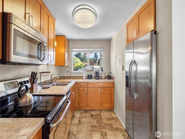 8828 S K St, Tacoma, WA 98444 - kitchen featuring stainless steel appliances, stone finish flooring, brown cabinets, baseboards, and a sink