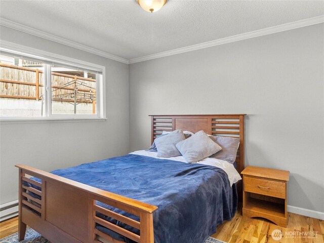 8828 S K St, Tacoma, WA 98444 - bedroom featuring wood finished floors, crown molding, baseboards, a textured ceiling, and a baseboard heating unit
