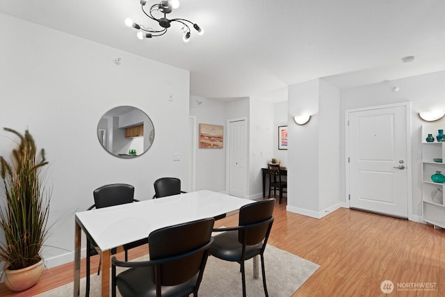 2331 42nd Ave SW Unit 206, Seattle, WA 98116 - dining area with light wood-style floors, baseboards, and a chandelier
