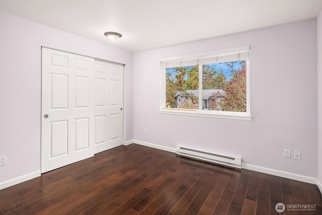 11113 NE 125th Ln Unit E-319, Kirkland, WA 98034 - unfurnished bedroom featuring a baseboard heating unit, baseboards, dark wood-style flooring, and a closet