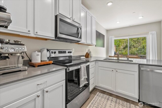 8603 E Gilman Ave, Arlington, WA 98223 - kitchen featuring stainless steel appliances, a sink, light wood-style floors, white cabinets, and recessed lighting