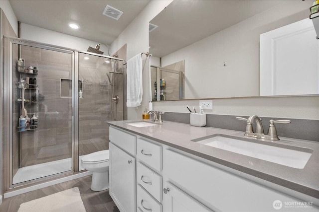 8603 E Gilman Ave, Arlington, WA 98223 - bathroom featuring toilet, double vanity, a stall shower, wood finished floors, and recessed lighting