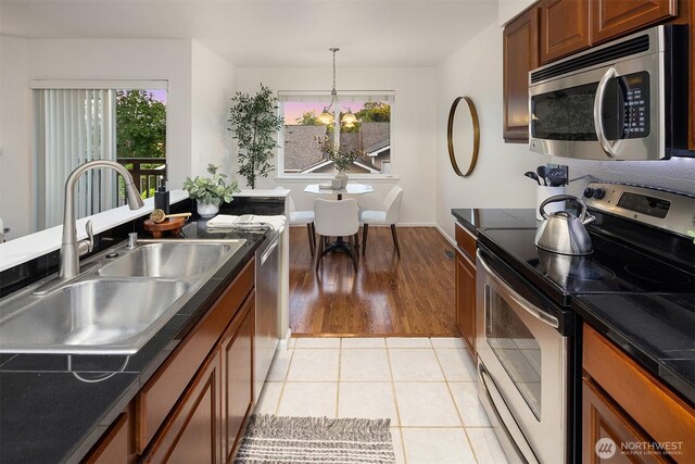 901 E Marine View Dr Unit 106, Everett, WA 98201 - kitchen featuring stainless steel appliances, a sink, brown cabinetry, dark countertops, and baseboards