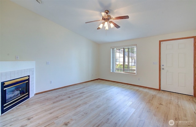 712 SE 5th Way, Battle Ground, WA 98604 - unfurnished living room featuring light wood finished floors, a ceiling fan, a tiled fireplace, and baseboards