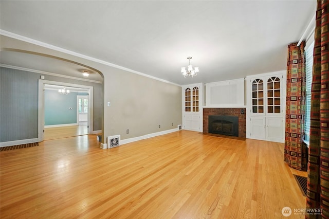 827 Hobson St, Walla Walla, WA 99362 - unfurnished living room featuring a chandelier, light wood finished floors, a brick fireplace, baseboards, and crown molding