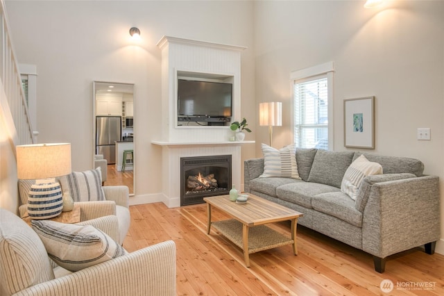 191 Compass St, Pacific Beach, WA 98571 - living area featuring a high ceiling, light wood-type flooring, and a glass covered fireplace