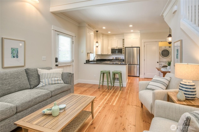 191 Compass St, Pacific Beach, WA 98571 - living room with stacked washing machine and dryer, light wood finished floors, ornamental molding, and recessed lighting