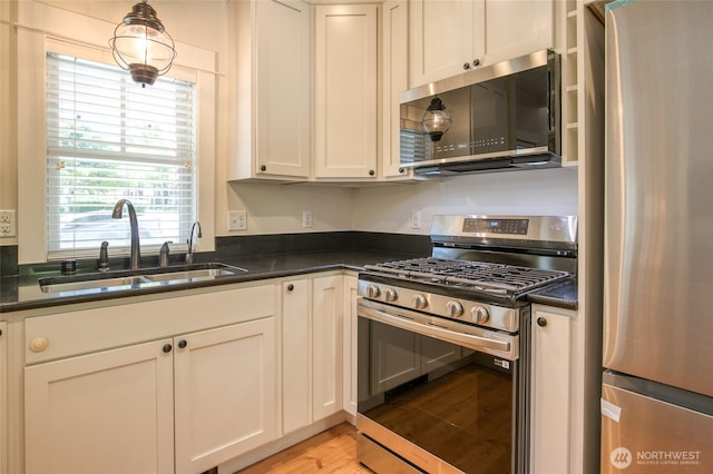 191 Compass St, Pacific Beach, WA 98571 - kitchen featuring appliances with stainless steel finishes, dark countertops, light wood-type flooring, and white cabinetry