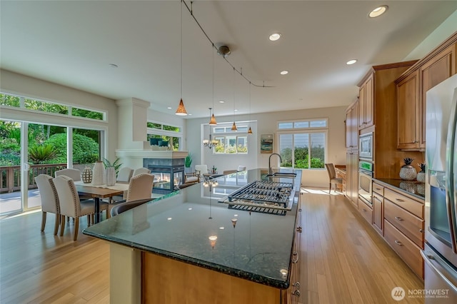 22879 NE 127th Way, Redmond, WA 98053 - kitchen with stainless steel appliances, a large island, brown cabinetry, recessed lighting, and plenty of natural light