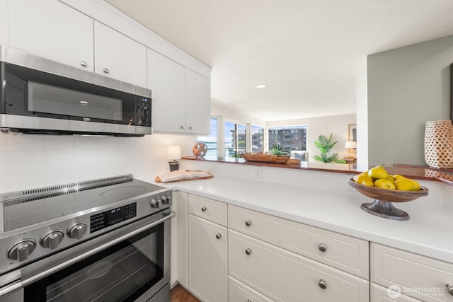 2360 43rd Ave E Unit 213, Seattle, WA 98112 - kitchen featuring appliances with stainless steel finishes, white cabinetry, light countertops, and tasteful backsplash
