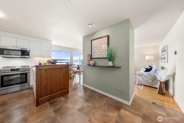 2360 43rd Ave E Unit 213, Seattle, WA 98112 - kitchen featuring stainless steel appliances, white cabinets, and baseboards