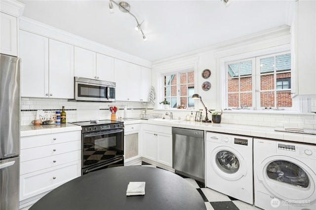 100 W Highland Dr Unit 404, Seattle, WA 98119 - kitchen with appliances with stainless steel finishes, separate washer and dryer, white cabinets, tile counters, and backsplash