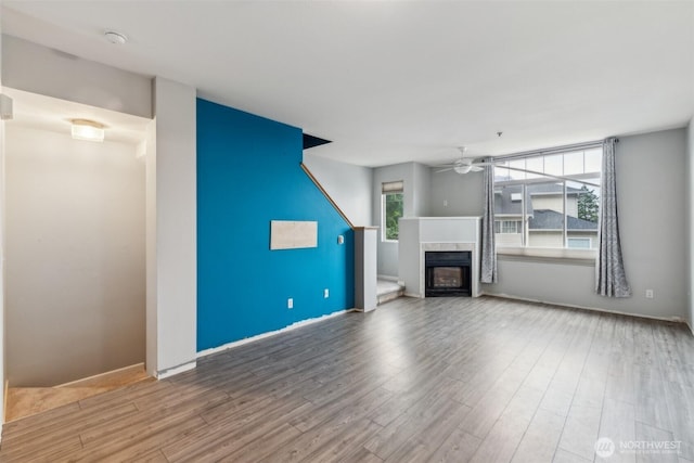 4724 Mill Pond Dr SE Unit 702, Auburn, WA 98092 - unfurnished living room featuring a ceiling fan, wood finished floors, a tiled fireplace, and baseboards