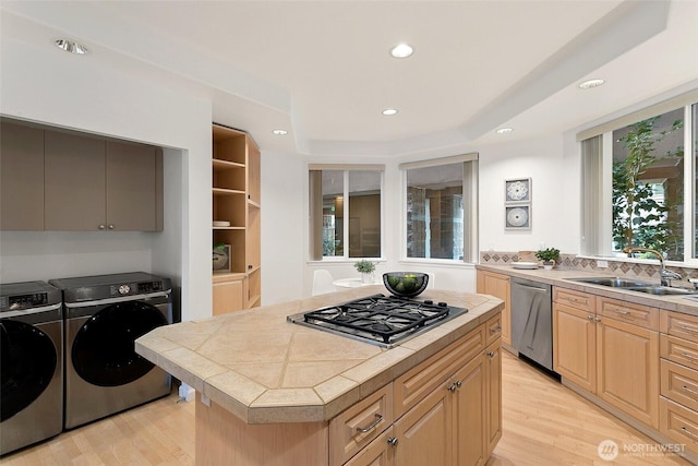 3900 2nd Ave NE Unit 204, Seattle, WA 98105 - kitchen with stainless steel appliances, washing machine and clothes dryer, a sink, light wood finished floors, and recessed lighting