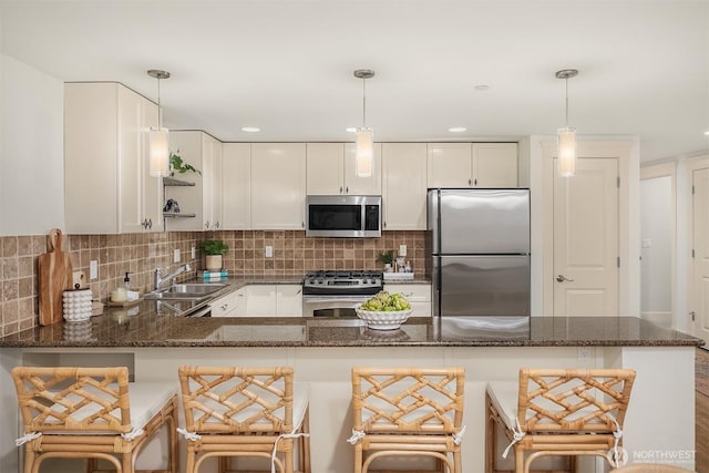 1414 1st Ave W Unit 104, Seattle, WA 98119 - kitchen featuring stainless steel appliances, white cabinetry, dark stone counters, and decorative light fixtures