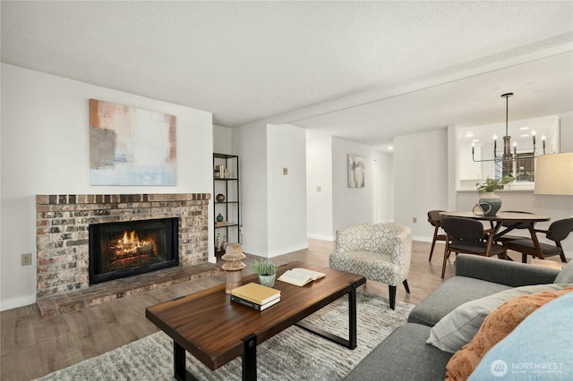 12721 NE 116th St Unit F102, Kirkland, WA 98034 - living room featuring light wood-style floors, a brick fireplace, baseboards, and a chandelier