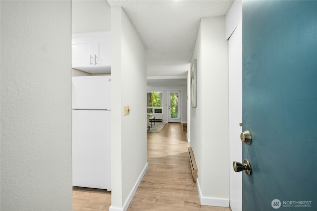 12721 NE 116th St Unit F102, Kirkland, WA 98034 - corridor featuring light wood finished floors, baseboards, and a baseboard radiator