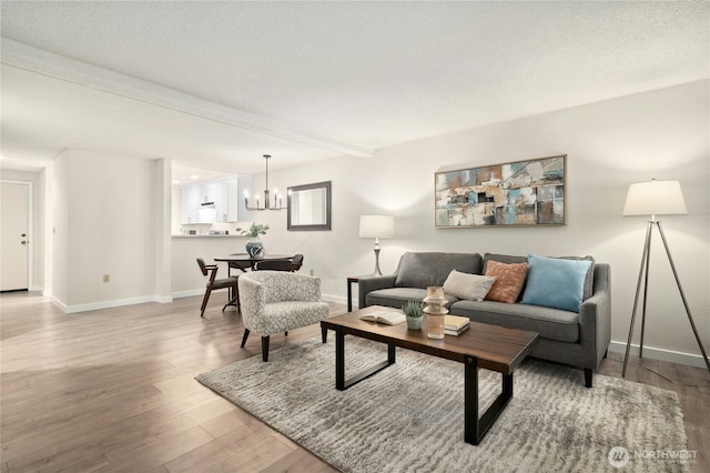 12721 NE 116th St Unit F102, Kirkland, WA 98034 - living room featuring a chandelier, baseboards, light wood-style flooring, and a textured ceiling
