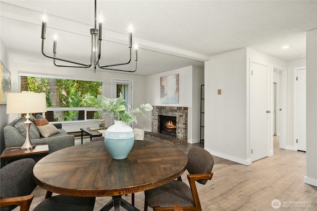 12721 NE 116th St Unit F102, Kirkland, WA 98034 - dining space with light wood-type flooring, baseboards, a fireplace, and a chandelier