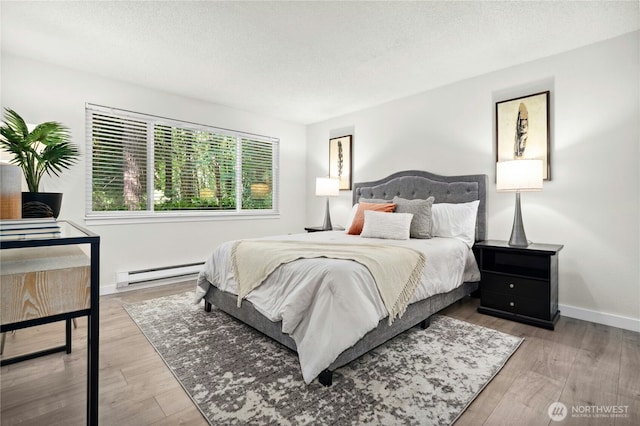 12721 NE 116th St Unit F102, Kirkland, WA 98034 - bedroom with a baseboard heating unit, a textured ceiling, wood finished floors, and baseboards