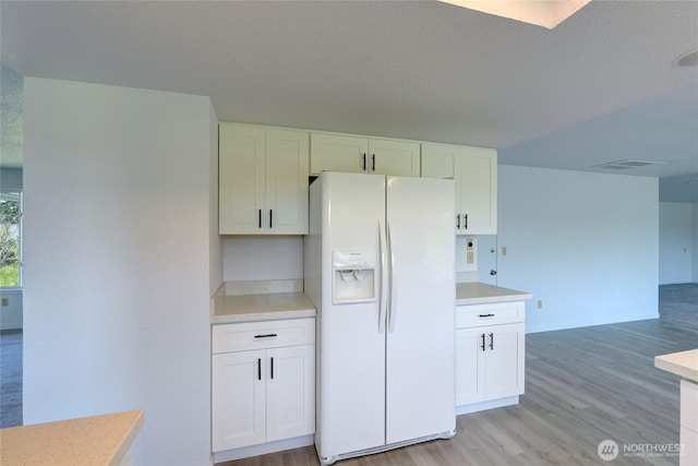 2320 183rd Street Ct E, Tacoma, WA 98445 - kitchen with white refrigerator with ice dispenser, light wood finished floors, white cabinetry, light countertops, and open floor plan