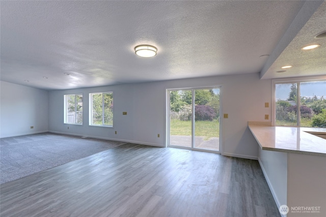 2320 183rd Street Ct E, Tacoma, WA 98445 - unfurnished living room featuring a textured ceiling, plenty of natural light, baseboards, wood finished floors, and recessed lighting