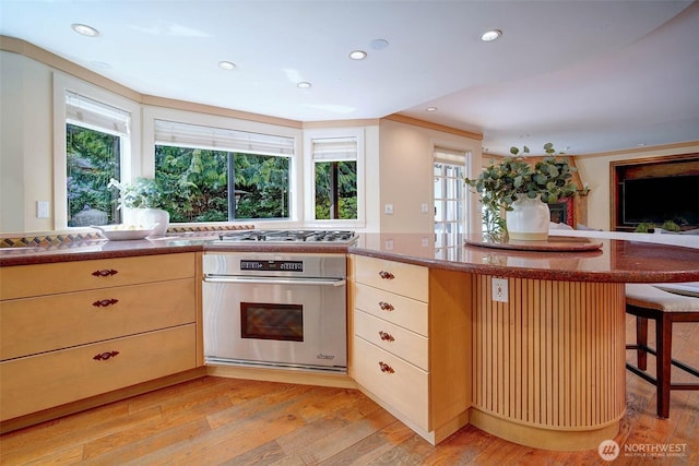2120 Squak Mountain Loop SW, Issaquah, WA 98027 - kitchen featuring appliances with stainless steel finishes, light wood-style flooring, a kitchen breakfast bar, recessed lighting, and light brown cabinetry