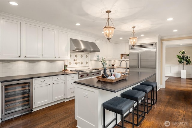 1325 Broadmoor Dr E, Seattle, WA 98112 - kitchen with beverage cooler, wall chimney exhaust hood, dark countertops, white cabinetry, and ornamental molding