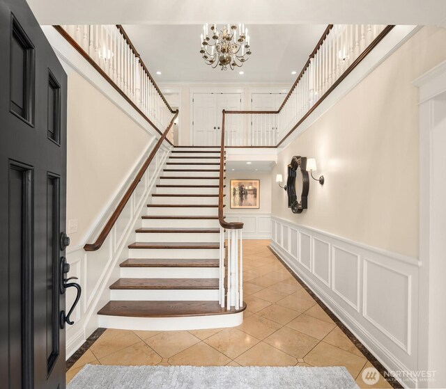 1325 Broadmoor Dr E, Seattle, WA 98112 - entrance foyer featuring a decorative wall, stairs, a high ceiling, light tile patterned floors, and a chandelier