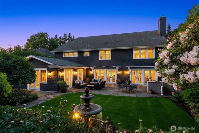 1325 Broadmoor Dr E, Seattle, WA 98112 - back of house at dusk featuring french doors, a patio area, a yard, a chimney, and an outdoor hangout area