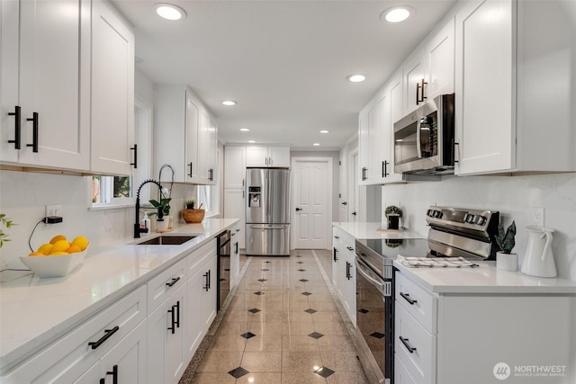 8048 S Ainsworth Ave, Tacoma, WA 98408 - kitchen featuring appliances with stainless steel finishes, a sink, recessed lighting, white cabinetry, and inlaid floor details