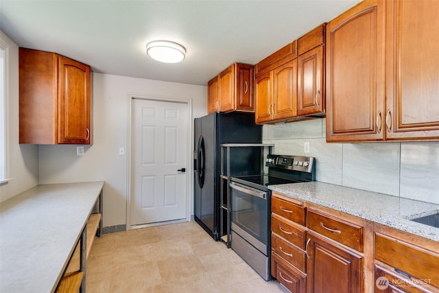 8048 S Ainsworth Ave, Tacoma, WA 98408 - kitchen with stainless steel electric range oven, brown cabinets, black fridge with ice dispenser, backsplash, and light stone countertops