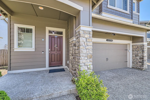 12726 36th Pl NE, Lake Stevens, WA 98258 - property entrance featuring stone siding, an attached garage, and concrete driveway