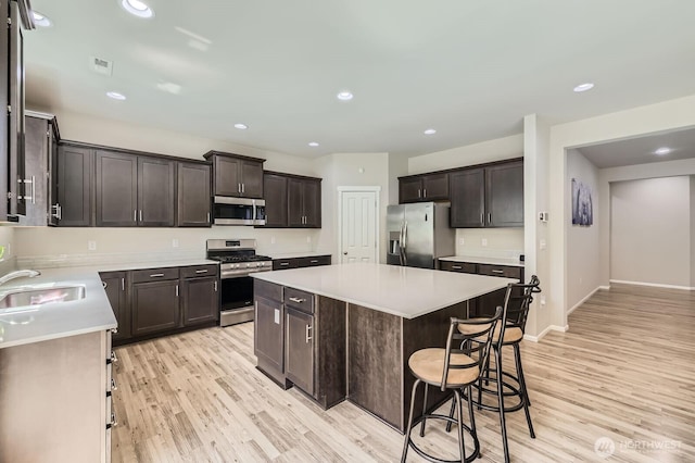 12726 36th Pl NE, Lake Stevens, WA 98258 - kitchen with stainless steel appliances, a sink, light wood-style flooring, a kitchen island, and light countertops