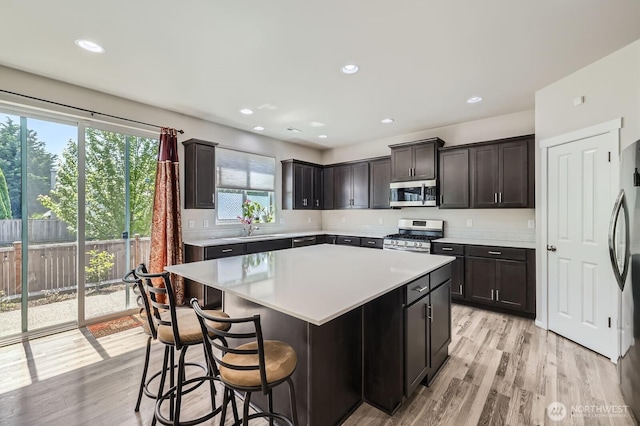 12726 36th Pl NE, Lake Stevens, WA 98258 - kitchen featuring appliances with stainless steel finishes, light countertops, light wood finished floors, a center island, and a breakfast bar