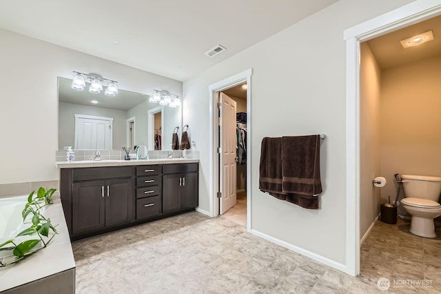 12726 36th Pl NE, Lake Stevens, WA 98258 - bathroom featuring double vanity, toilet, baseboards, and a walk in closet