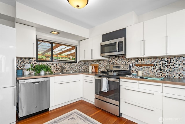4742 22nd Ave SW, Seattle, WA 98106 - kitchen with appliances with stainless steel finishes, a sink, dark wood finished floors, tasteful backsplash, and white cabinetry