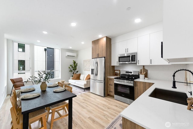 8324 16th Ave NW Unit A, Seattle, WA 98117 - kitchen with stainless steel appliances, a sink, light countertops, decorative backsplash, and light wood finished floors
