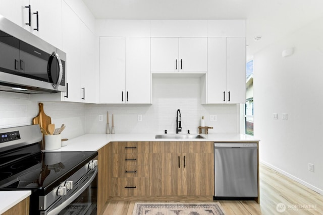 8324 16th Ave NW Unit A, Seattle, WA 98117 - kitchen with stainless steel appliances, a sink, light wood-style flooring, and light countertops