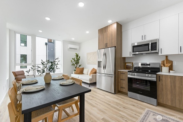 8324 16th Ave NW Unit A, Seattle, WA 98117 - kitchen with stainless steel appliances, a wall mounted air conditioner, light wood-type flooring, backsplash, and light countertops